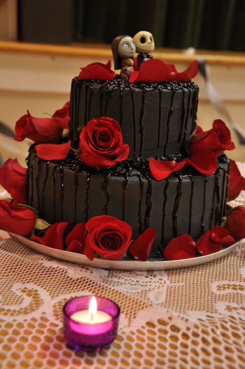 a black buttercream wedding cake with bloody dripping, red roses and petals, Sally and Jack Skellington toppers for a Halloween wedding