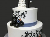a white patterned wedding cake with a ribbon, sugar blooms and skeleton toppers is a stylish and easy idea for a Halloween wedding