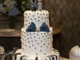 a white, grey and blue wedding cake with various patterns and a blue bow plus quirky toppers for a Halloween wedding