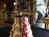 a white buttercream wedding cake with many patterns, blood drips, a bloody zombie bride topper for a Halloween wedding
