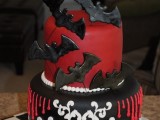 a black, red and white wedding cake with patterns and chocolate bats is a creative idea for a Halloween wedding