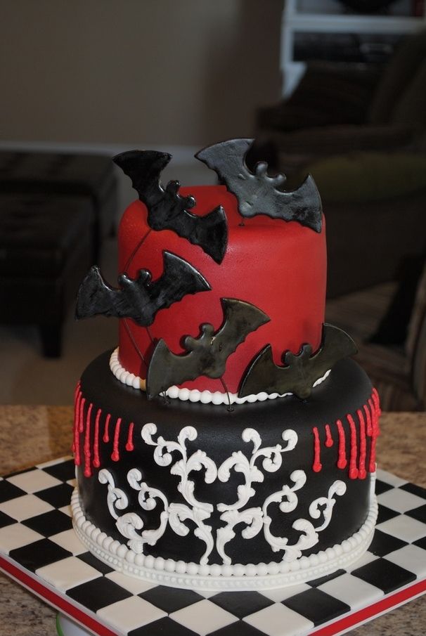 A black, red and white wedding cake with patterns and chocolate bats is a creative idea for a Halloween wedding