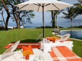a bright picnic setting with colorful blankets, umbrellas and bright blooms by the pool