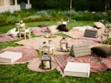 a boho summer picnic with lots of rugs, pillows, books and candle lanterns for a rehearsal dinner