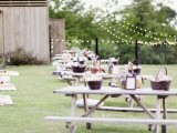 rustic benches and tables plus baskets with food and drinks and blooms and signs on each table