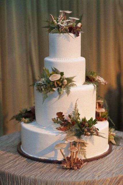 a beautiful woodland fall wedding cake in white decorated with leaves, berries and mushrooms is a lovely idea to go for