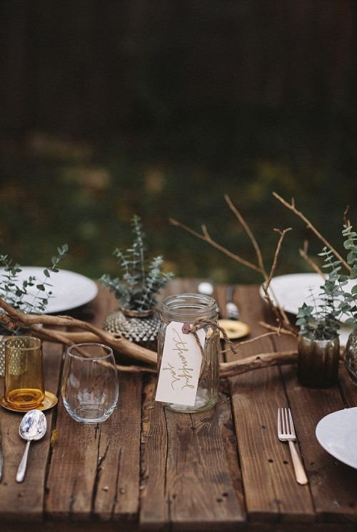 a simple and all-natural fall wedding tablescape with an uncovered table, branches and eucalyptus is a beautiful idea for a woodland wedding