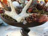 a fall woodland wedding centerpiece of a tall stand with moss, antlers, acorns, pinecones, eggs, leaves and much more