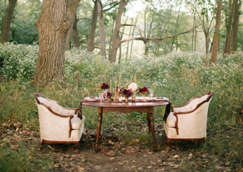 a fall woodland elopement reception space with bold blooms, neutral chairs, candles and elegant gold touches