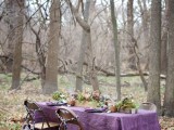 a moody fall woodland wedding tablescape with a purple tablecloth, candles, some flowers and greenery is a statement solution for a woodland wedding