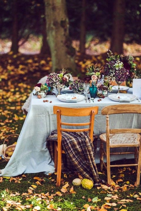 a bold fall woodland wedding reception right in the forest, with jewel tone arrangements and bold glasses, plaid chair covers is ideal