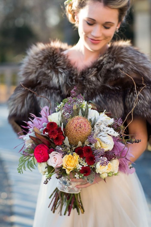 a fall woodland bride in a fur cover up and with a bold wedding bouquet for a fall woodland wedding in jewel tones