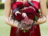 a bridesmaid bouquet with black callas and red blooms plus soem textural leaves