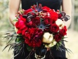 a black strapless wedding dress with a lush wedding bouquet of red blooms and dark and green foliage
