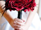 a wedding bouquet of red blooms with a black wrap contrasts the neutral wedding dress
