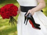 black shoes with red bottoms and a red rose bouquet and a black sash for the bride