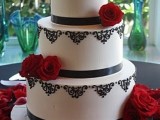 a black and white wedding cake topped with red roses served on red petals is a chic idea