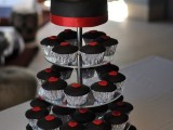 black cupcakes with red hearts on top plus a black wedding cake with red ribbons and cake toppers