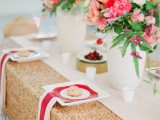 a gold sequin tablecloth, striped napkins, a printed plate and bright red and pink florals for centerpieces