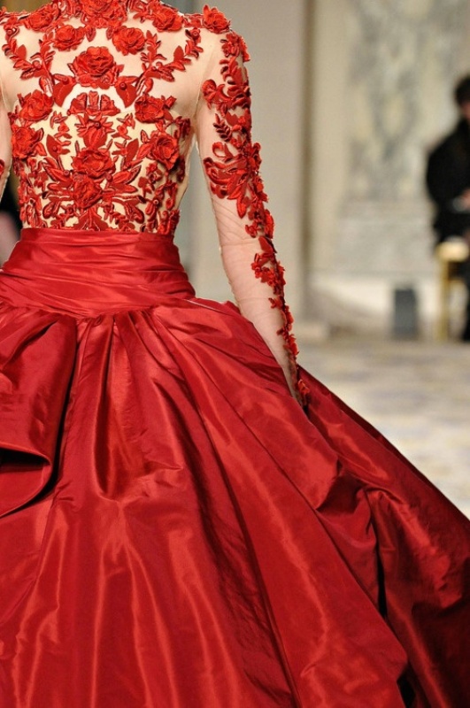 A formal A line wedding dress with a nude and red applique bodice and a full layered skirt plus illusion sleeves