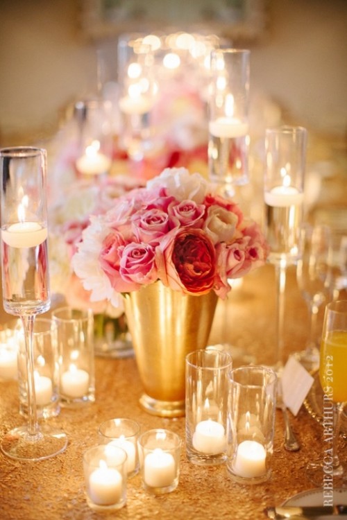 a gold vase with pink roses and candles in glass candleholders for a glam wedding table setting