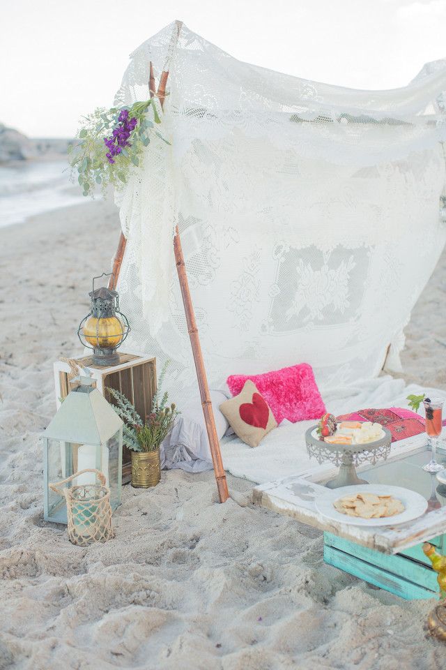 a boho beach teepee done with boho lace, colorful pillows, candle lanterns, blooms and greenery