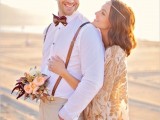 a simple boho beach groom’s outfit with tan pants, a white shirt, suspenders and a printed bow tie