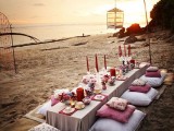 a boho beach picnic setting with  with a low table, boho rugs and colorful pillows, lanterns and colorful candles