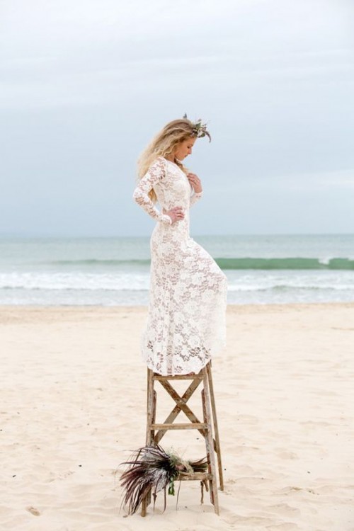 a fitting boho beach wedding dress with long sleeves, a high neckline, a feather hairpiece for a boho bride