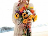 a simple and neutral boho beach wedding dress with a lace trim on the skirt and sleeves plus a bright bouquet