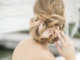 a delicate twisted ribbon updo with a volume on top and blush ribbon is a refined idea that may be rocked for a wedding