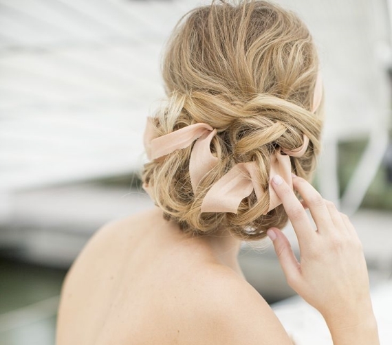 A delicate twisted ribbon updo with a volume on top and blush ribbon is a refined idea that may be rocked for a wedding