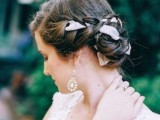 a chic and refined braided low updo with a blush ribbon that accents the hair and matches the wedding dress