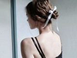 a messy twisted and braided low bun accented with a small white ribbon is a refined and chic idea to rock