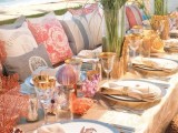 a bright beach wedding tablescape with woven placemats, seagrass, seashells and corals plus a burlap runner