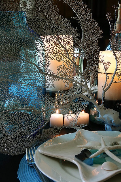 a sea tablescape with candles, corals, blue placemats and a starfish plate on top for a coastal feel