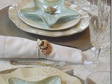 a neutral beach tablescape with neutral plates, starfish ones, elegant glasses and seashell napkin rings