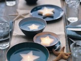 a minimal beach wedding table with a neutral table runner, blue bowls with floating star candles and blue napkins