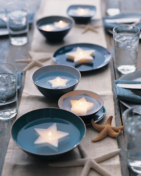 a minimal beach wedding table with a neutral table runner, blue bowls with floating star candles and blue napkins