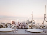 a neutral beach wedding tablescape with lots of corals, seashells, neutral candles and porcelain