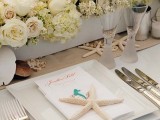 a neutral wedding tablescape with white blooms, seashells and starfish, square plates and a starfish on top