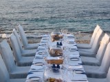 a simple and romantic beach wedding table with blue vases, plates, wooden boxes for bread and neutral napkins