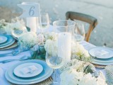 a beautiful light blue and neutral beach wedding tablescape with neutral blooms, blue plates and glasses and woven placemats