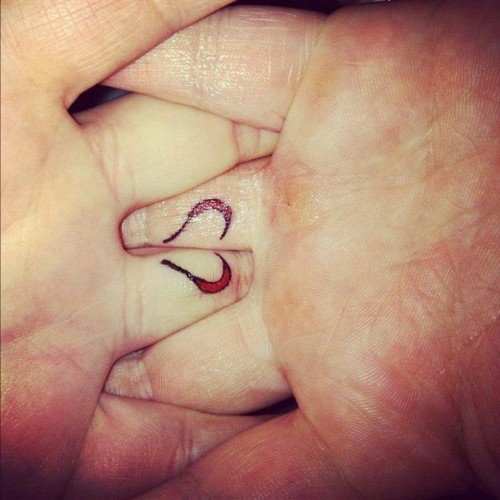 a mini red heart tattoo on the back of the ring finger that is divided into two parts is a very delicate thing