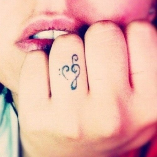 a treble clef heart-shaped tattoo on the ring figer is a lovely idea for those who love music