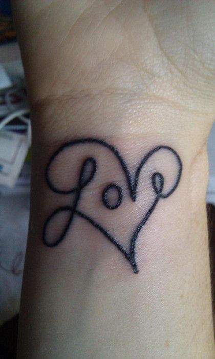 a large LOVE and heart tattoo on the wrist is a cool statement on your wedding day