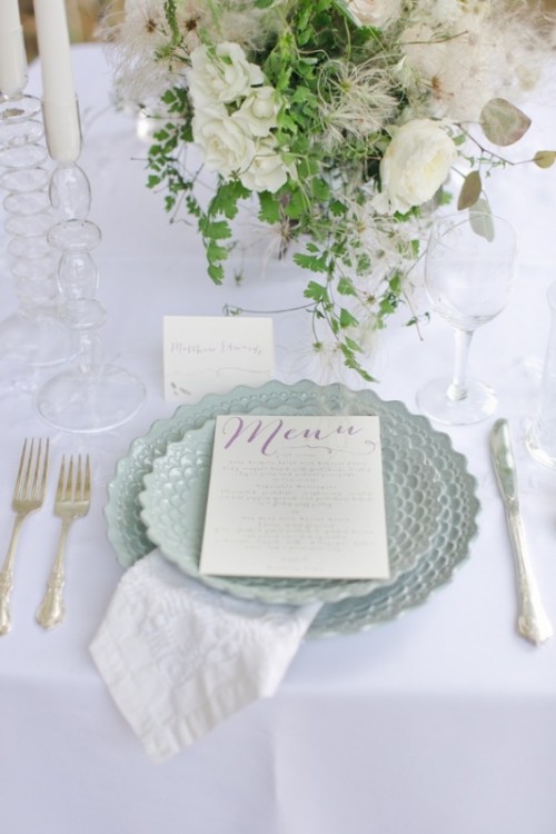 a chic vintage-inspired wedding tablescape with white florals and candles, pale blue porcelain, elegant vintage cutlery and embroidered napkins