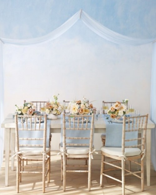 a pale blue wedding reception with a neutral reception space and pale blue napkins and placemats, neutral and pastel floral centerpieces