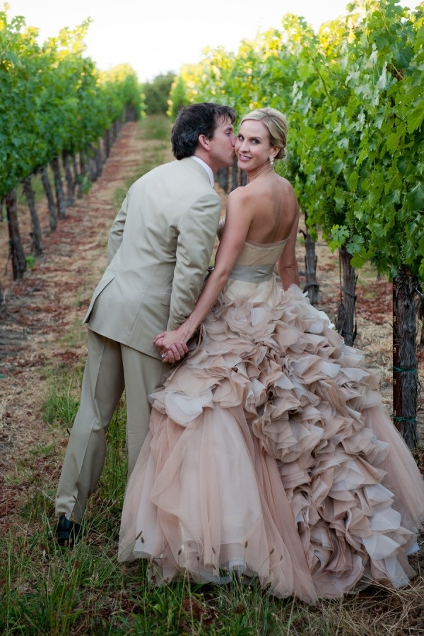 A dusty pink strapless wedding ballgown with a ruffled skirt and a silver sash for a chic vineyard wedding
