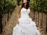 a strapless wedding ballgown with a draped bodice and a ruffled skirt plus a single spaghetti strap